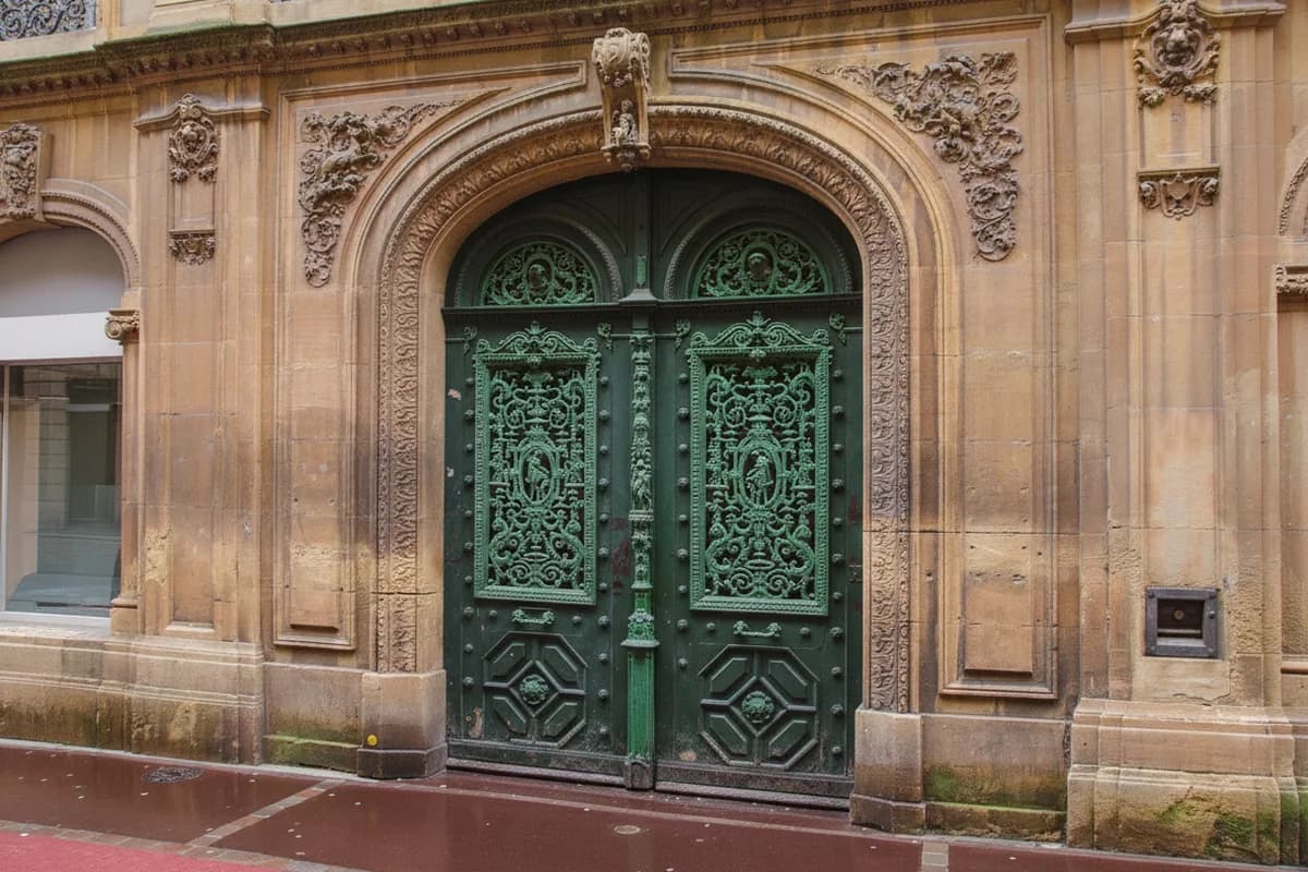 Porte d’entrée en bois d’un immeuble messin en pierre de Jaumont, ferrures anciennes et encadrement mouluré du quartier impérial