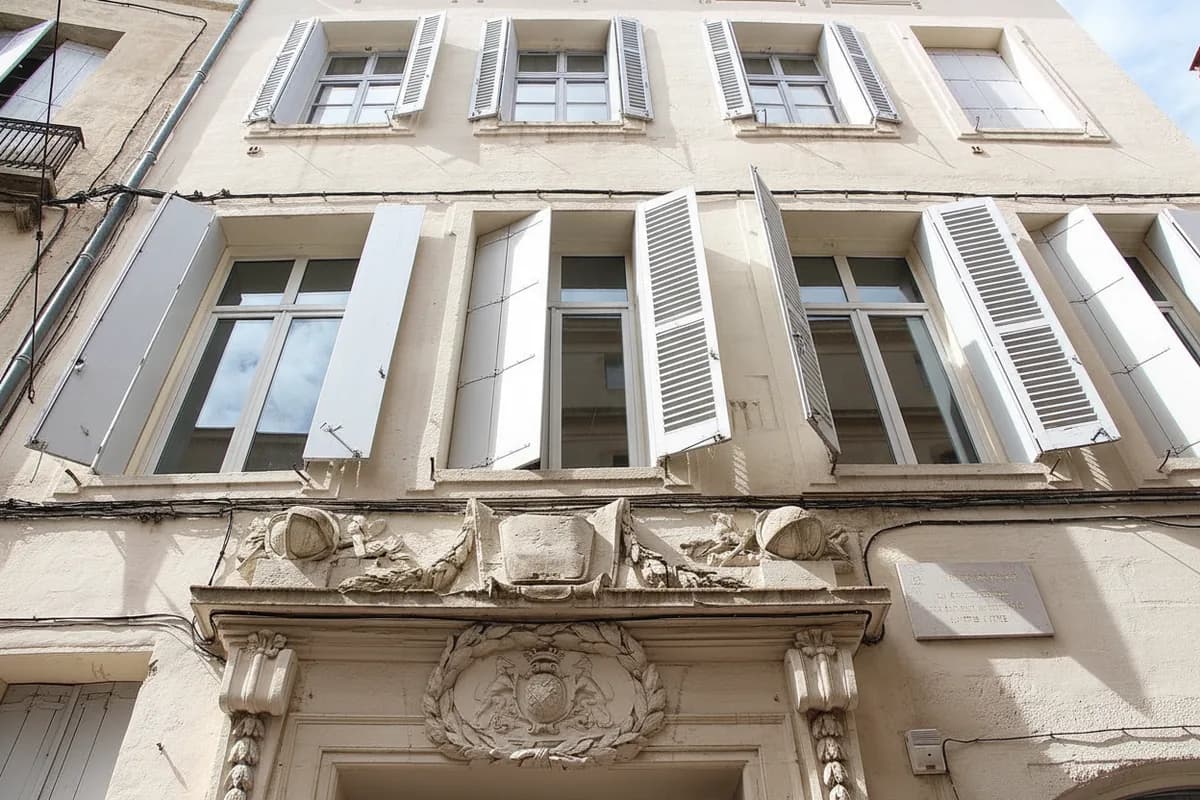 Façade d’immeuble ancien dans une rue étroite de l’Écusson à Montpellier, volets en bois et porte cochère