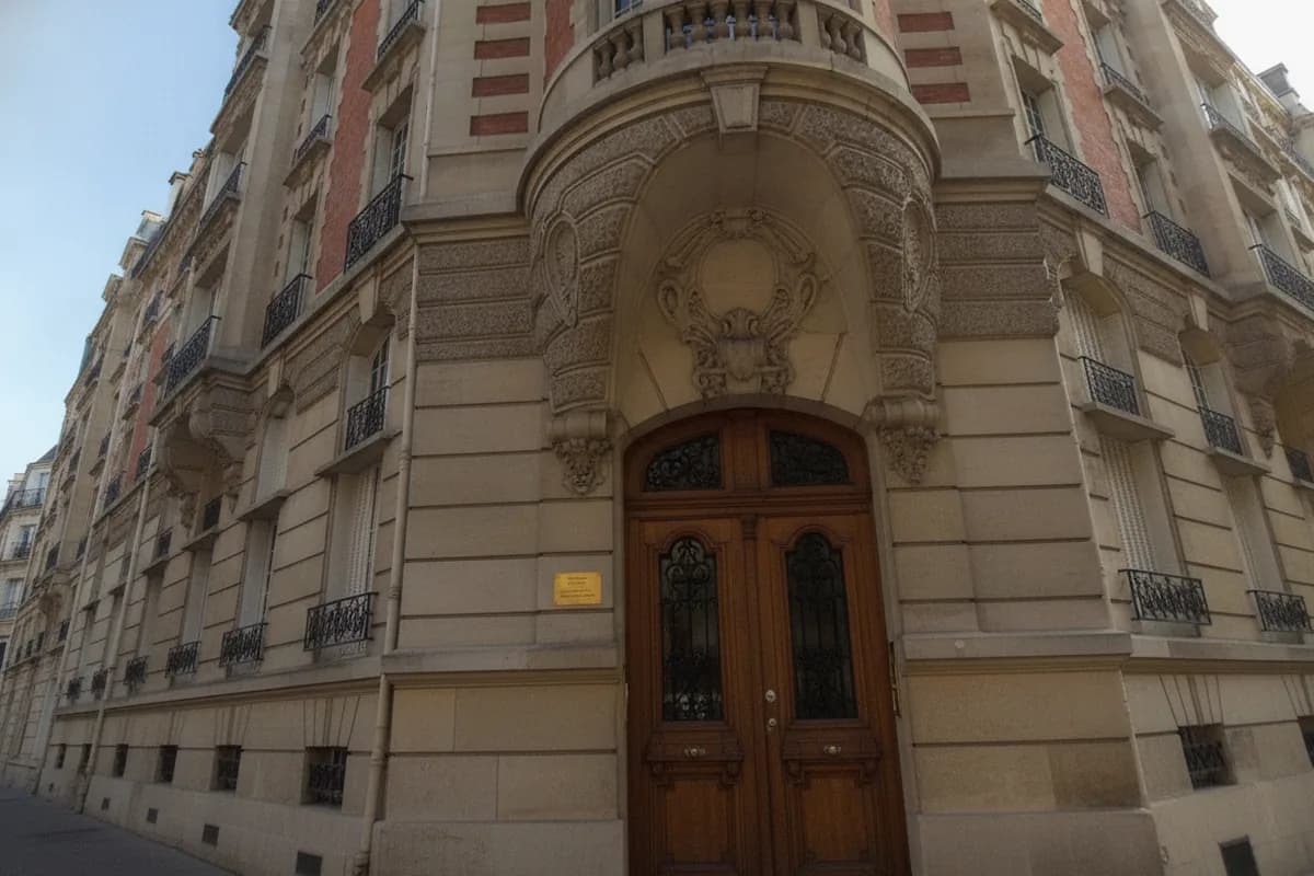 Porte cochère en bois sous un porche sculpté, à l’angle d’un immeuble parisien en pierre et brique Porte cochère en bois sous un porche sculpté, à l’angle d’un immeuble parisien en pierre et brique